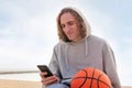 Smiling caucasian man in a hoodie using phone