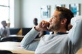 Smiling caucasian mid adult businessman with hand behind head talking on mobile phone in office Royalty Free Stock Photo