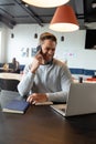 Smiling caucasian mid adult businessman talking on mobile phone in creative office Royalty Free Stock Photo