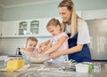 Smiling caucasian mother with two adorable daughters baking at home. Mom and kids mixing batter or ingredients in bowl Royalty Free Stock Photo