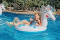 Smiling Caucasian red-haired  girl lying on inflatable ring unicorn. Kid child enjoying having fun in swimming pool. Summer Royalty Free Stock Photo