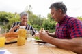 Smiling caucasian senior man holding hamburger eating meal with wife in garden Royalty Free Stock Photo