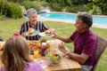 Smiling caucasian senior man serving family before eating meal together in garden Royalty Free Stock Photo