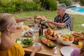 Smiling caucasian senior woman serving family before eating meal together in garden Royalty Free Stock Photo