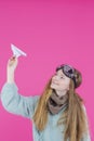 Smiling Caucasian Teenage Girl in Flying Glasses and Knitted Sweater Launching Origami Paper Plane While Posing Over Pink Royalty Free Stock Photo