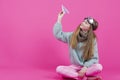 Smiling Caucasian Teenage Girl in Flying Glasses and Knitted Sweater Launching Origami Paper Plane While Posing Over Pink Royalty Free Stock Photo