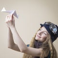 Smiling Caucasian Teenager Girl in Flying Glasses Launching Origami Paper Plane Over Beige Background Royalty Free Stock Photo