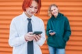 Smiling caucasian teens friends boy and a girl portraits browsing their smartphone devices. Careless young teenhood time and a