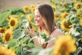 Smiling Caucasian woman with blond hair smelling sunflower in farm on sunny day Royalty Free Stock Photo