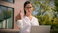 Smiling Caucasian woman girl female businesswoman freelancer student using laptop in city outdoors showing thumbs up Royalty Free Stock Photo