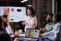 Smiling caucasian woman in late night meeting presenting business analytics to happy team