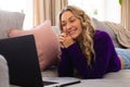 Smiling caucasian woman lying on couch looking at laptop in sunny living room Royalty Free Stock Photo