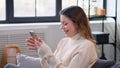 Smiling Woman Messaging In Social Media Using Phone At Home