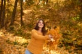 Smiling caucasian woman in yellow sweater throwing autumn leaves laughing in colorful forest foliage Royalty Free Stock Photo