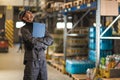 Smiling caucasian worker with clipboard looking up in warehouse. Royalty Free Stock Photo