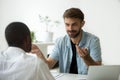 Smiling Caucasian worker talking to black colleague in office