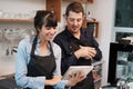 Smiling Caucasian Young barista couple love is wearing apron and working in the coffee shop. Woman is writing order and menu with Royalty Free Stock Photo