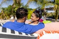 Smiling caucasian young couple looking at each other while relaxing on loungers at tourist resort Royalty Free Stock Photo