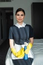 smiling chambermaid in rubber gloves holding