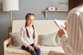 Smiling charming girl in psychologist office talking with doctor, schoolgirl patient psychotherapy consultation children trauma Royalty Free Stock Photo