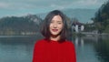 Smiling cheerful asian woman wearing casual red sweater posing for the camera Beautiful girl walking near the lake and