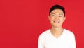 Asian young man's portrait on red studio background. Concept of human emotions, facial expression, youth, sales, ad. Royalty Free Stock Photo