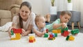 Smiling cheerful baby, boy and mother palying toys on carpet at home. Concept of family having time together and Royalty Free Stock Photo