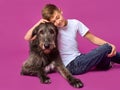 Smiling cheerful eleven years teen in white t-shirt and jeans with brown big dog on fuchsia color background in photo studio.