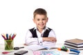 Smiling cheerful excellent pupil sitting still at the desk with white background