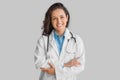 Smiling cheerful female doctor wearing white uniform and stethoscope standing with folded arms and smiling at camera Royalty Free Stock Photo