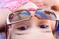 Smiling, cheerful girl is lying in a big retro pair of sunglasses. The concept of summer fun. Small depth of view, focus on