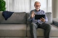 Smiling cheerful happy senior man waving and gesturing to camera having online video call on hand held tablet portable device Royalty Free Stock Photo