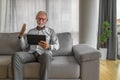 Smiling cheerful happy senior man waving and gesturing to camera having online video call on hand held tablet portable device Royalty Free Stock Photo