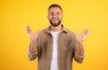 Smiling cheerful inspired handsome young european guy with beard in casual spreads arms to sides