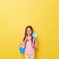 Smiling cheerful little cute girl with dark hair holding beach sandbox toys rake and shovel isolated over yellow background Royalty Free Stock Photo