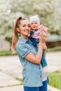 Smiling cheerful mother hugs baby girl in denim jumpsuit Royalty Free Stock Photo