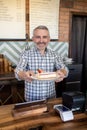 Smiling cheerful pastry shop employee serving dessert to a customer