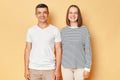 Smiling cheerful positive man and woman wearing casual clothing standing isolated over beige background posing together looking at Royalty Free Stock Photo