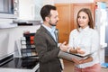 Smiling polite saleswoman helping man to choose materials for kitchen furniture in shop