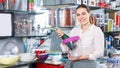 Smiling young woman buying ware for wine bottle in cookware shop