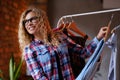 Smiling cheerful woman in glasses and checkered shirt chooses clothes in butique for her holidays