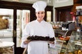 Smiling woman seller showing sweet drizzled cake Royalty Free Stock Photo