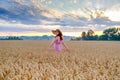 Smiling cheerful woman in wheat field turn around with outstretched arms at dawn