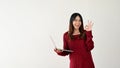 A smiling Asian female college student is holding a laptop and showing the Okay hand sign Royalty Free Stock Photo