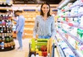 Young smiling woman shopping in supermarket with trolley cart Royalty Free Stock Photo