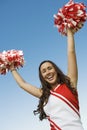 Smiling Cheerleader rising pom-poms Royalty Free Stock Photo