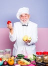 Smiling chef with blackboard and vegetables. Chef garnishing food in the kitchen. Chef leaning on the counter with a Royalty Free Stock Photo