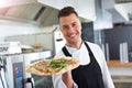 Smiling chef holding fresh pizza in kitchen Royalty Free Stock Photo