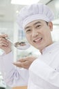 Smiling chef with spoon lifted to his mouth, tasting food, portrait Royalty Free Stock Photo