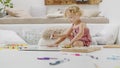 Smiling child, beautiful little girl with blue eyes and curly blonde hair, draws and writes cheerfully playing with coloured pens Royalty Free Stock Photo